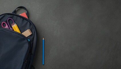 A dark blue backpack filled with school supplies on a textured, dark surface.