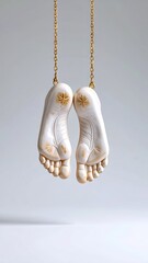 Golden chain-suspended sculpted feet art, creative representation of weightlessness, delicate design
