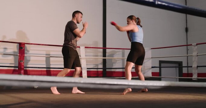 Coach and trainee stepping into boxing ring, performing gloved feint jabs, slipping in training
