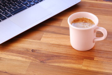 淹れたての美味しいコーヒー、カフェ・ラッテを飲みながら、ノートパソコンでデスクワークをしているイメージ
