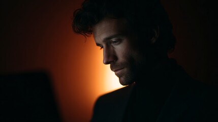 Man looking down with thoughtful expression illuminated by warm light 77 characters