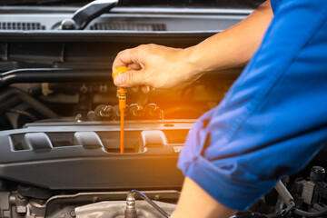 A mechanic's hand checks the engine oil level and he is about to change the engine oil