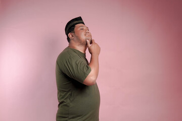 A man in a green shirt is looking down at his chin. He is deep in thought