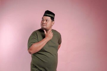 A man in a green shirt is looking down at his chin. He is deep in thought
