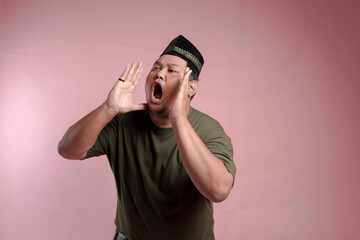 A man in a green shirt is screaming. The man is wearing a hat and has his hands on his head