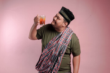  man in a green shirt and plaid robe holding a cup of tea. The man is smiling and he is enjoying...