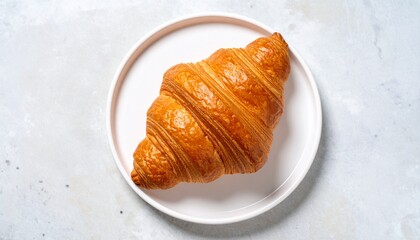 Golden brown croissant on a white plate, Freshly baked breakfast pastry, buttery and flaky in a minimalist setting