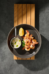 Fried shrimp with garlic and sauce, bright mood, overhead composition on dark ceramic plate