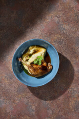 Duck leg with celery root puree under bright directional lighting, overhead composition
