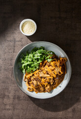 Tagliatelle pasta with mushroom bolognese and arugula, bright lighting, overhead composition