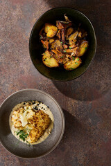 Cauliflower steak with creamy sauce in bright overhead shot, roasted potatoes and chanterelles...