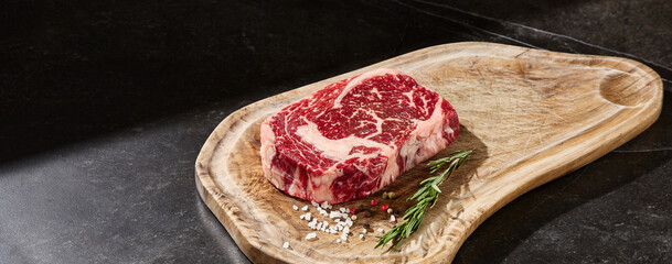 Ribeye steak on wooden board, bright lighting, minimal overhead composition for menu use