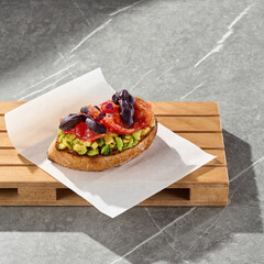 Bruschetta with salmon and avocado in bright natural lighting, overhead composition on stone surface