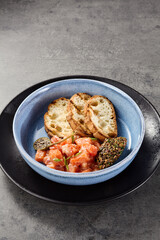 Salmon tartare plated with ciabatta and olive tapenade, bright natural light, overhead composition