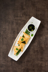Crab turnovers on a bright overhead white platter with brown rustic background