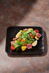 nicoise salad bright lighting overhead, seared tuna, rustic surface, gourmet restaurant presentation