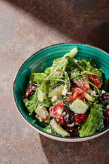 Greek salad bowl in bright overhead rustic setting with tomatoes, cucumber, olives, and feta