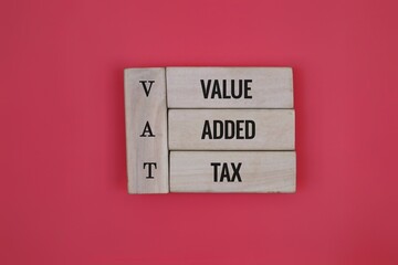 Wooden Block with the words VAT 'value, added, tax' on an red Background