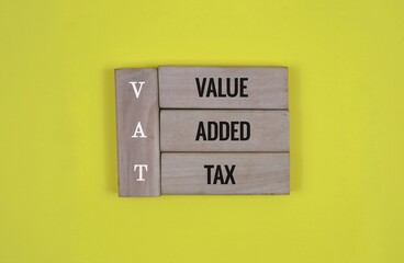 Wooden Block with the words VAT 'value, added, tax' on an yellow Background