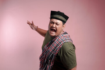 A man in a plaid scarf and a black hat is yelling. The man is angry and his face is red