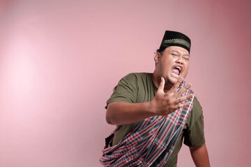 A man in a plaid scarf and a black hat is yelling. The man is angry and his face is red