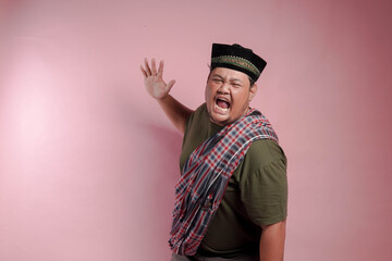 A man in a plaid scarf and a black hat is yelling. The man is angry and his face is red