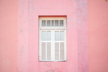 Vintage white window set in a textured pink wall, showcasing a minimalist architectural design