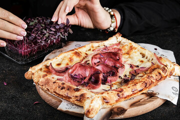 Enjoy a delicious pizza topped with various meats and microgreens