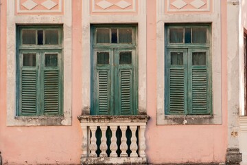 Obraz na płótnie Canvas Vintage architecture with green shutters on a pink wall, featuring a classic balustrade