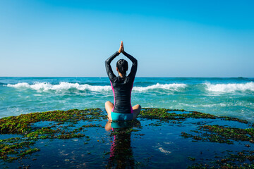 Yoga woman meditation at the seaside cliff edge facing the coming strong sea waves