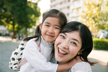 Happy asian mother and daughter are hugging in a park