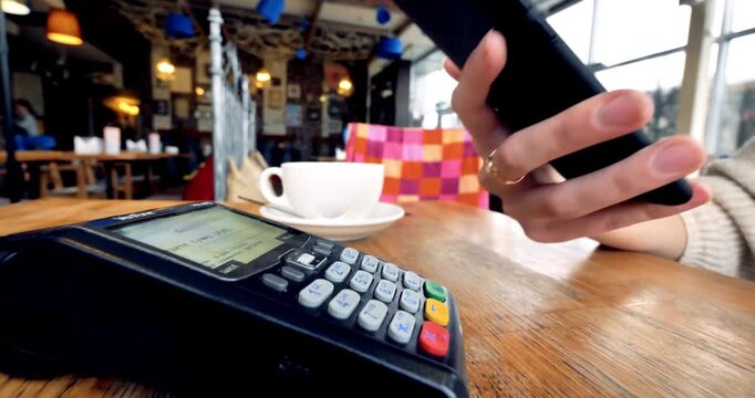 paying through smart phone using NFC technology. Close-up. 4K modern technology cafe shopping fashion green string counter