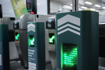 Rows of automatic entrance gates with green arrow direction signs in metro subway station