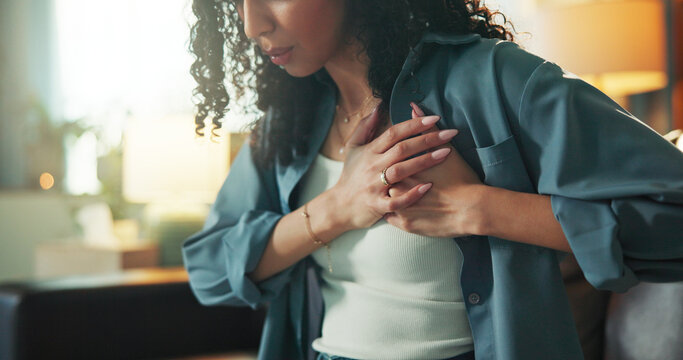 Heart attack, emergency and fear with woman on sofa for chest pain, angina and medical crisis. Cardiac arrest, hypertension and anxiety with person in living room of home for heartburn and risk
