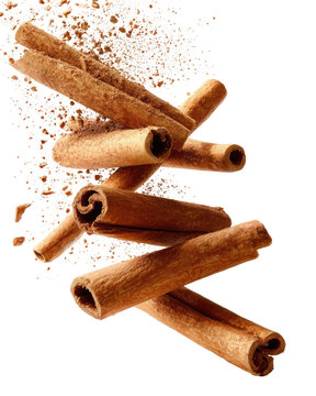 Cinnamon sticks, in motion, amidst a spray of ground cinnamon