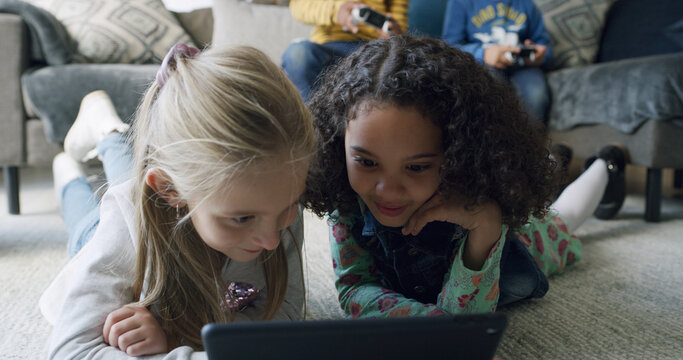 Relax, friends and kids with tablet in home for movie, internet app or streaming cartoon. Girls, living room and children with technology to watch show together, entertainment and smile on floor