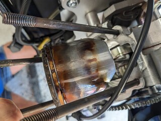 Heavily carboned piston and cylinder from a two-stroke aircraft engine after teardown, revealing...