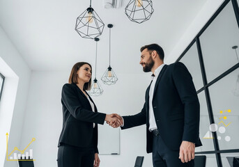 Confident business partners agree on deal shaking hands in modern office with data visuals