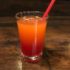 Vibrant layered cocktail in a shot glass, featuring a rich gradient from deep red to bright orange,...