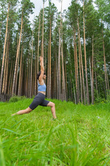 Female doing yoga in lush forest surrounded by tall trees