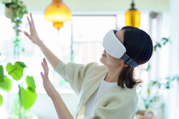 部屋でVRゴーグルを装着して、手探りをする女性