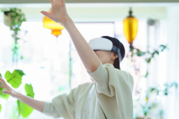部屋でVRゴーグルを装着して、手探りをする女性