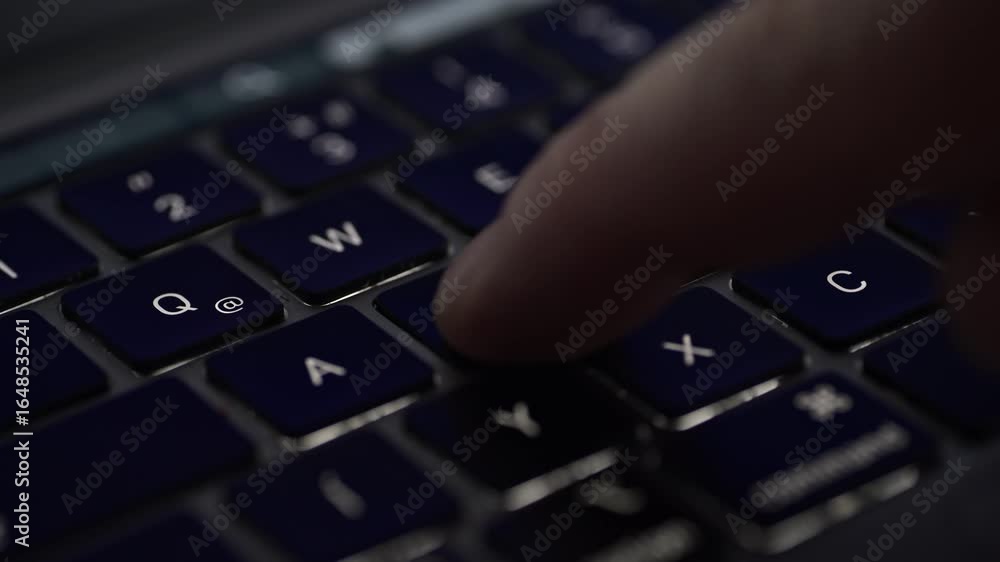Poster a close-up view of a person's finger pressing the s key on a dark-colored laptop keyboard. the image