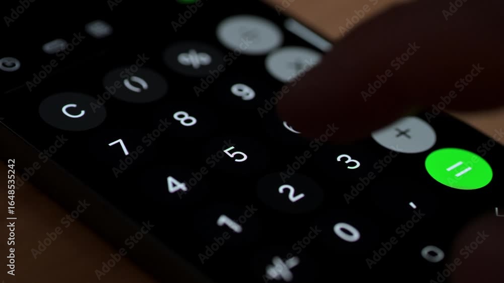 Poster a close-up view of a hand pressing a button on a smartphone calculator app. the dark interface is il