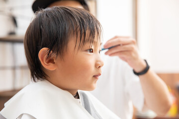 美容師に髪を切ってもらう子供