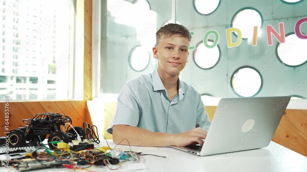 Poster smart teenager working on laptop and looking at camera at stem technology class. caucasian student u