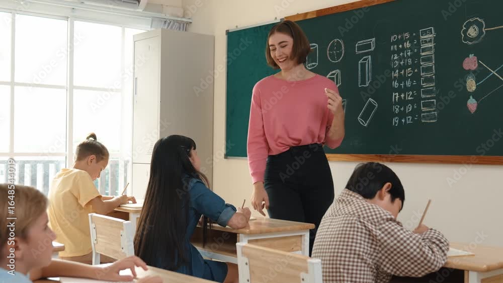 Poster Smart teacher checking cute student homework while explaining idea at class. Attractive instructor walking around classroom while looking at notebook and talking about Math theory to child. Pedagogy.