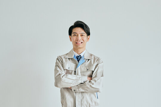 腕を組む作業服姿の若い男性