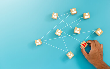 Hand placing key employee block into connected network;  teamwork, collaboration, and human...