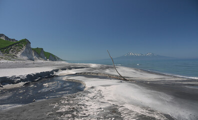 Iturup black sand beach with river mouth and volcano in background